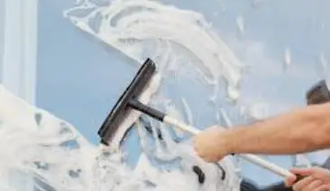 close up of squeegee on window with lots of suds